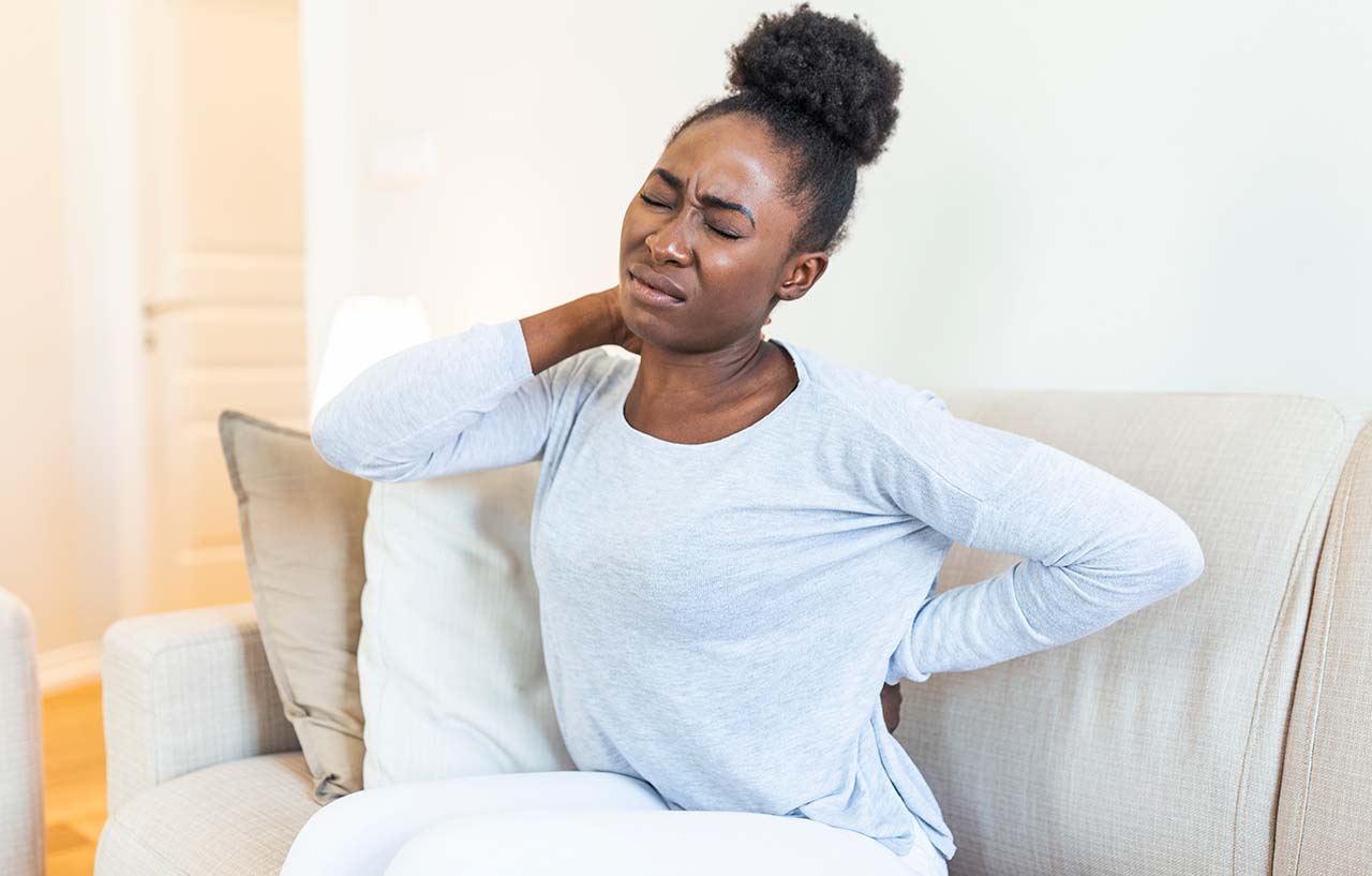 Woman suffering from pain in her back and neck needs physiotherapy for whiplash treatment