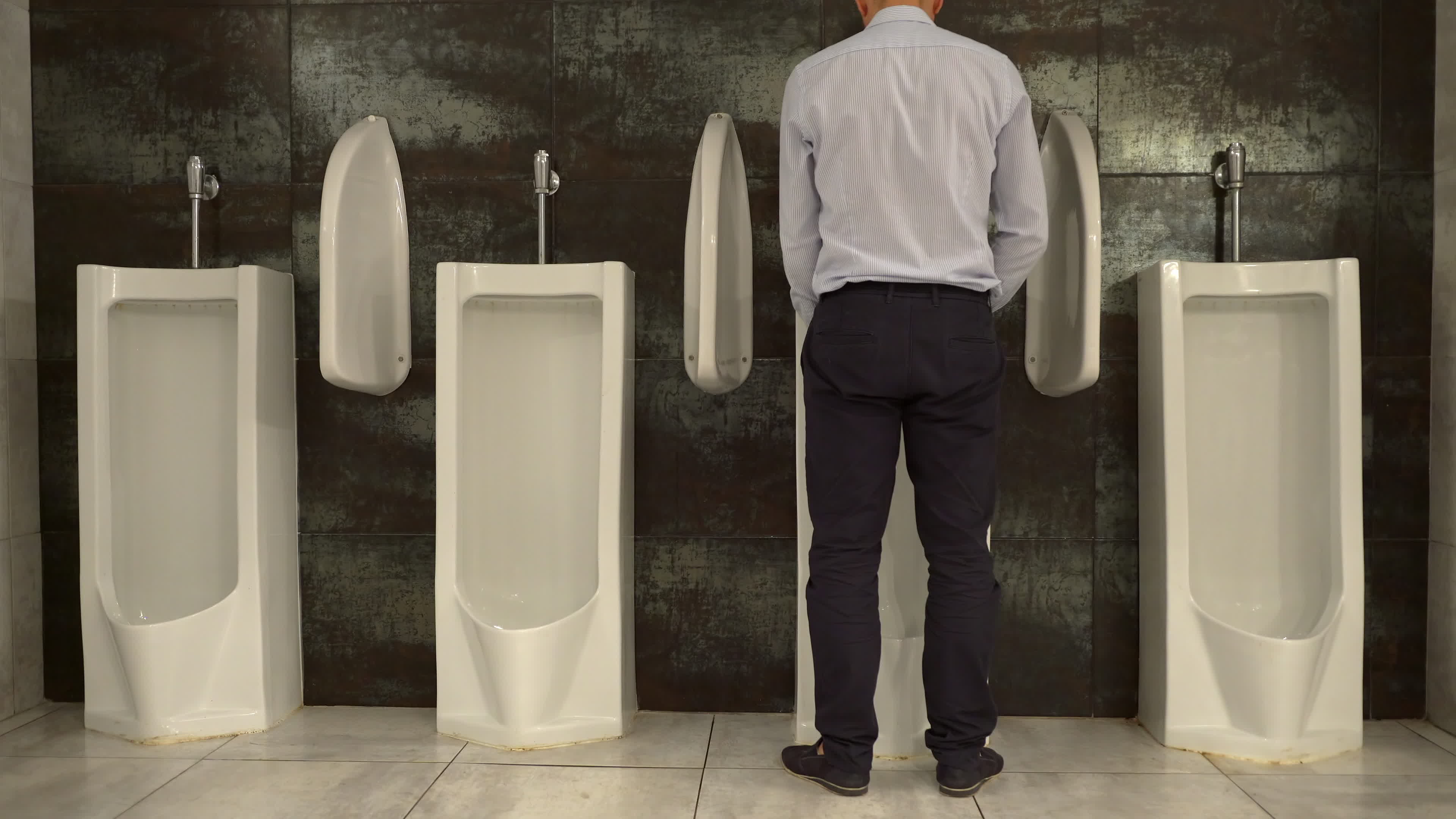 Man Peeing to Urinal in the Restroom