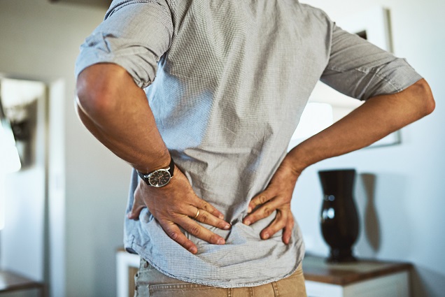 Man holds lower back in pain from pelvic floor problem