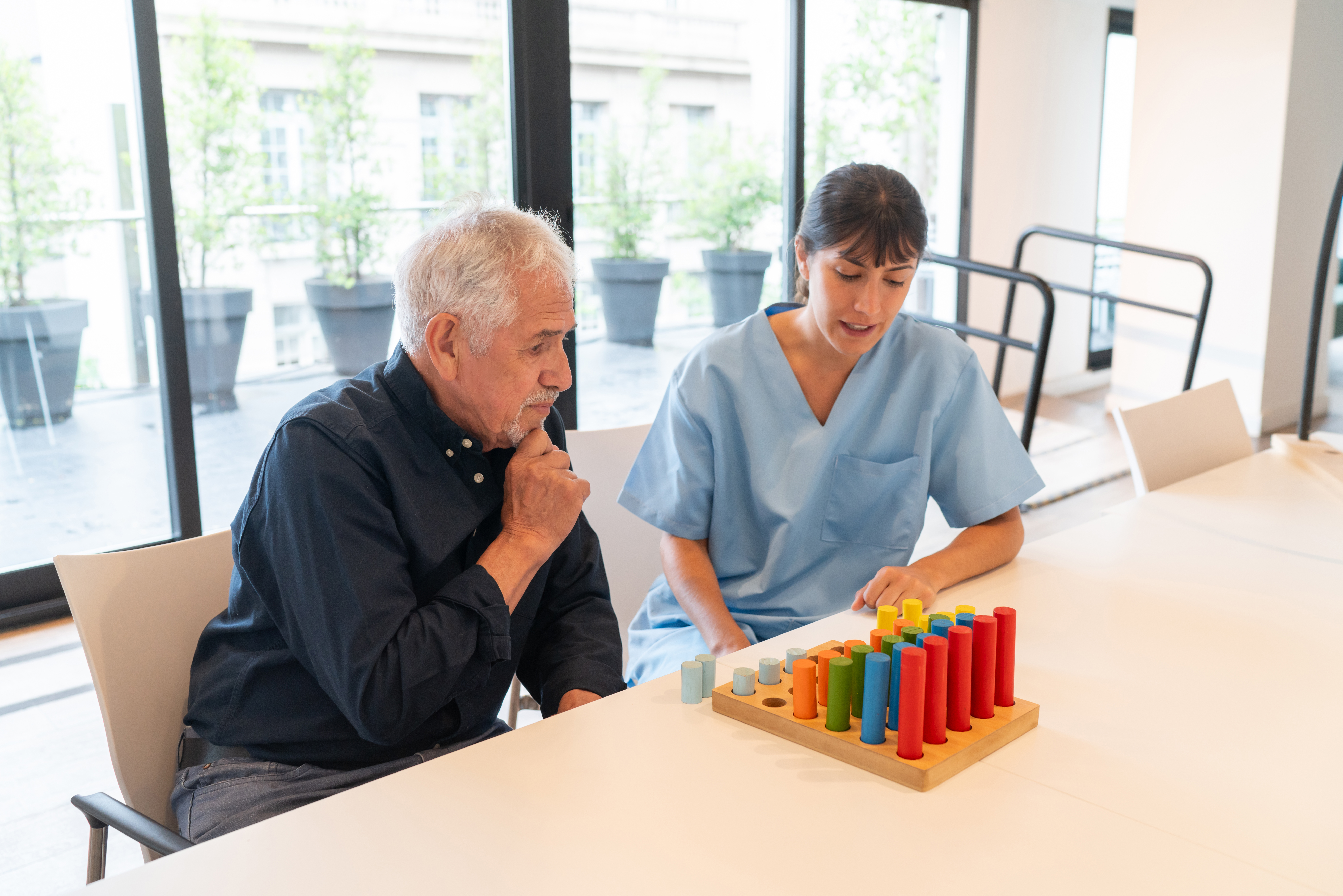An elderly man partaking in occupational therapy with a nurse