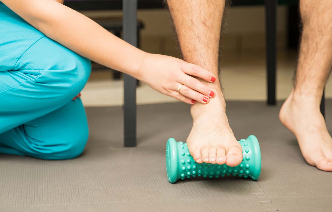 Physiotherapist assessing a patient for chronic ankle instability with a foot roller exercise