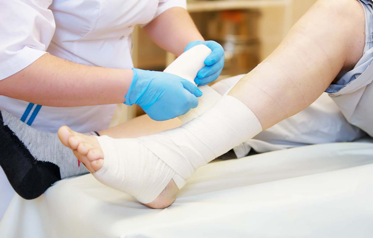 Nurse bandaging a patient's foot after ankle replacement surgery