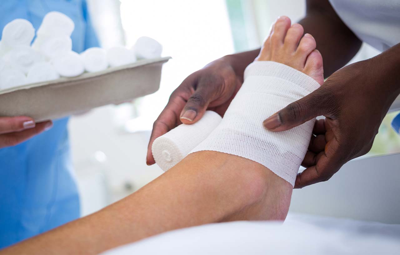 Clinician bandaging a patient's foot after their ankle arthroscopy surgery