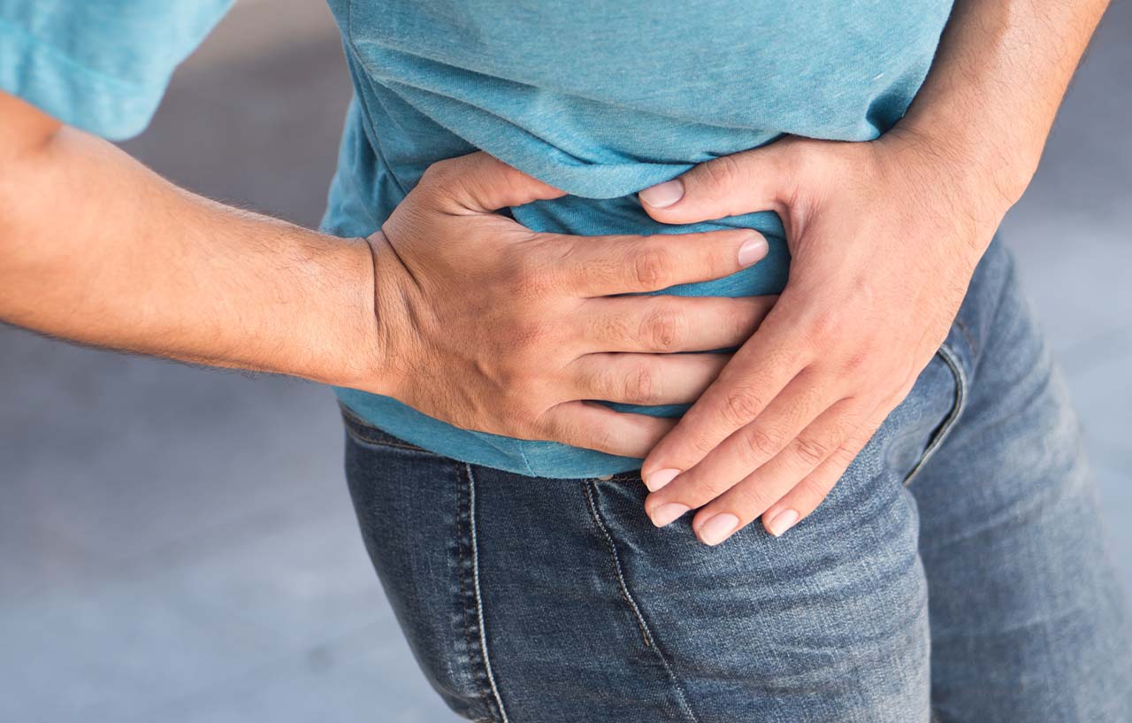 Person with hip pain placing their hands around their hip