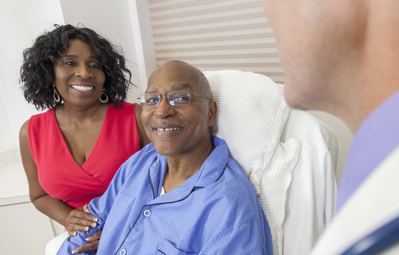 Husband and wife speaking to surgeon ahead of a procedure to remove benign scrotal lumps