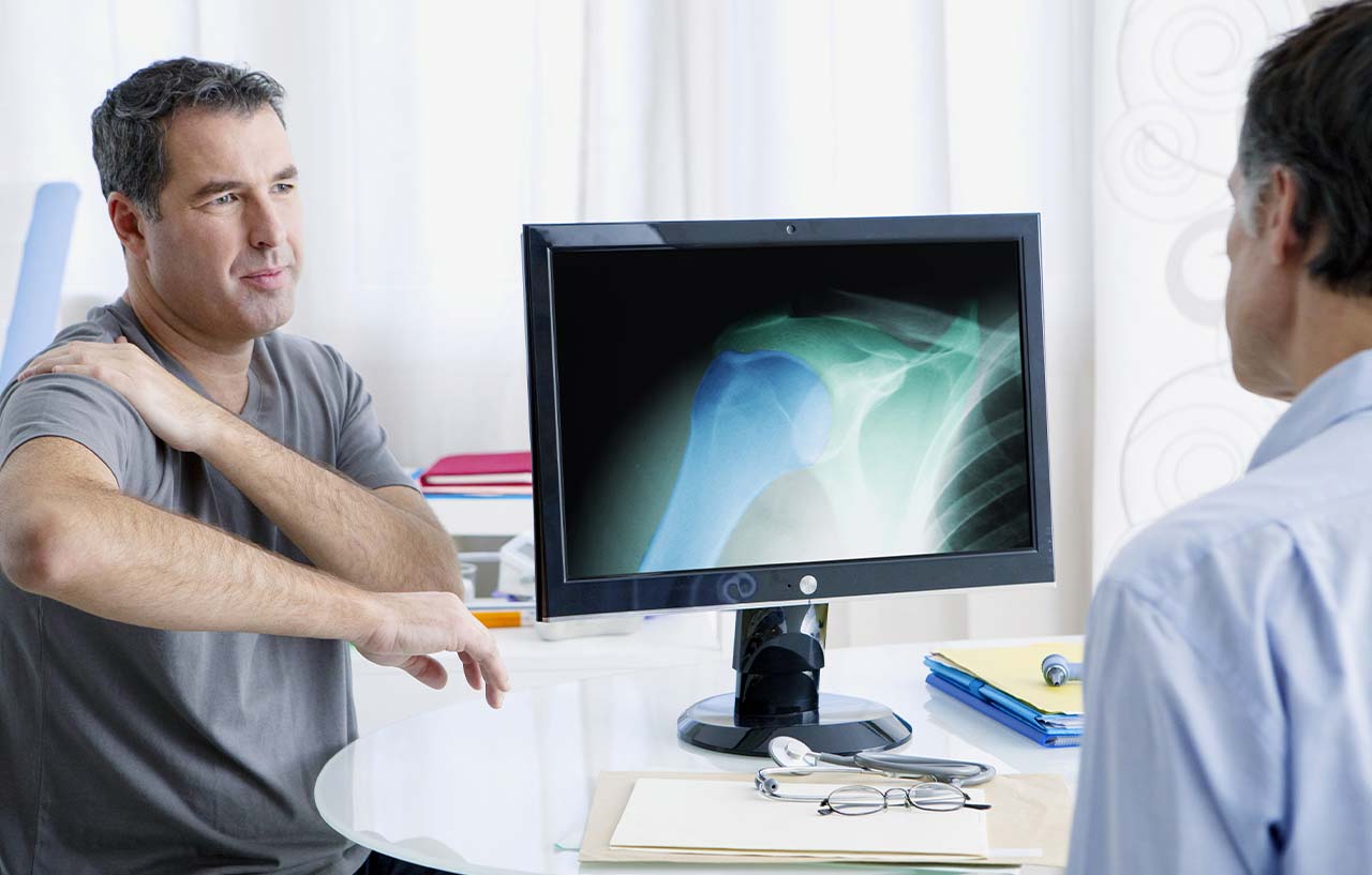 Man holding shoulder in pain as clinician considers comprehensive arthroscopic management as a treatment option