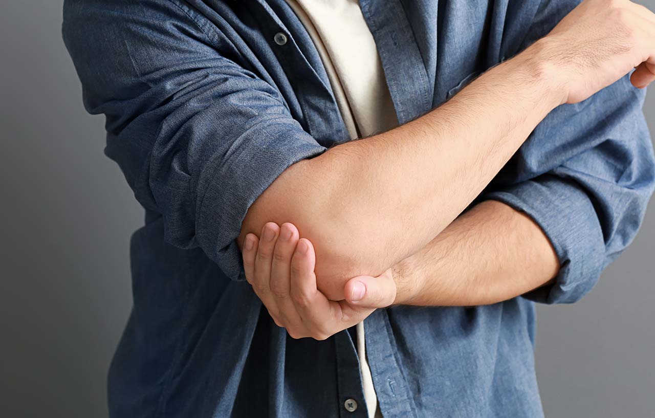 Male patient holding his hand on his painful elbow
