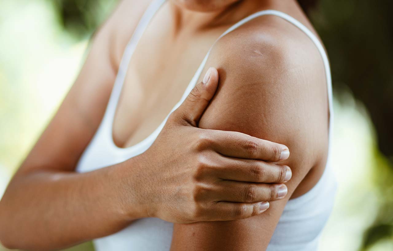 Woman needs thoracic outlet decompression surgery as she holds her shoulder in pain