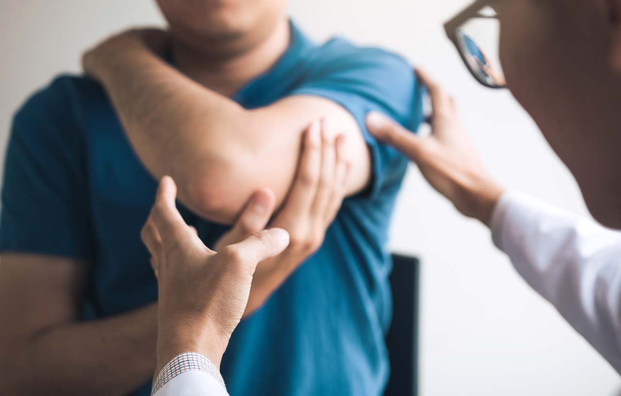 Specialist examines a patient's bent arm ahead of elbow replacement surgery