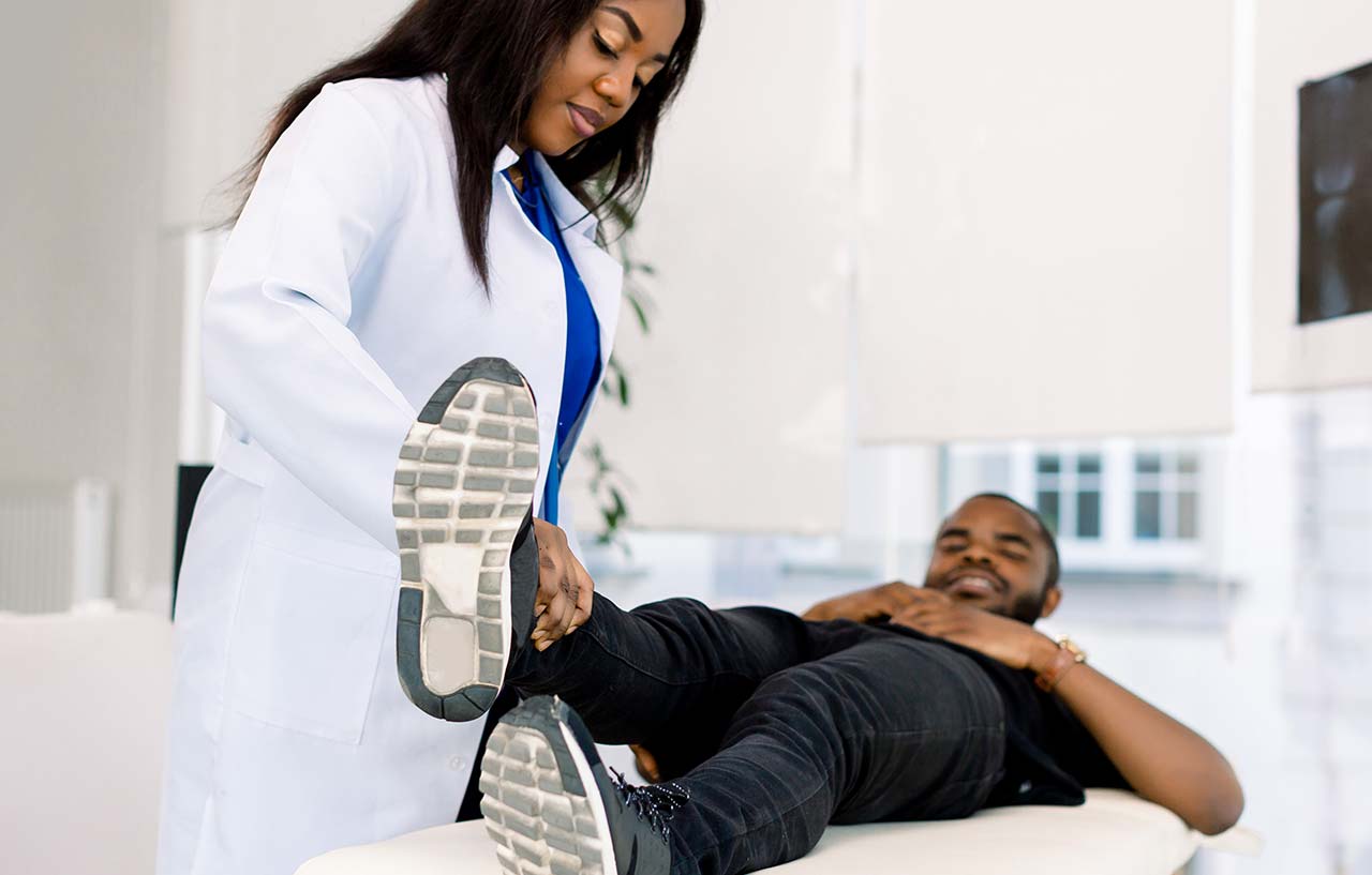 Doctor performing an exam on a patient's leg as part of his knee injury treatment