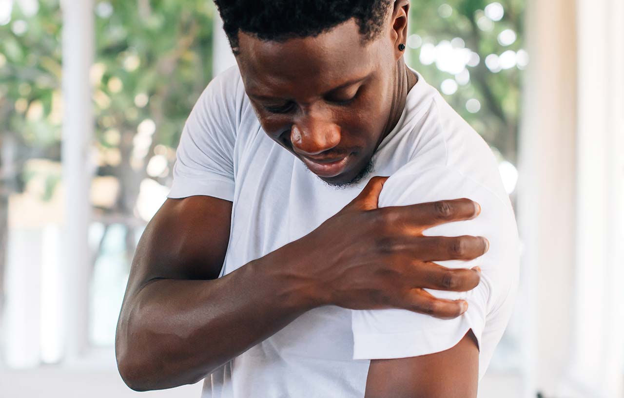 Man holding his arm in pain needs shoulder surgery
