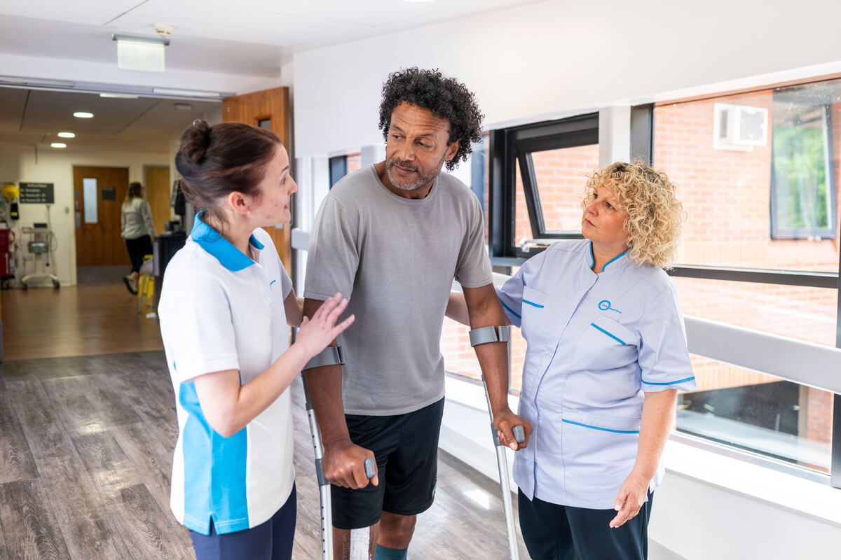 Private patient on crutches being supported by hospital staff