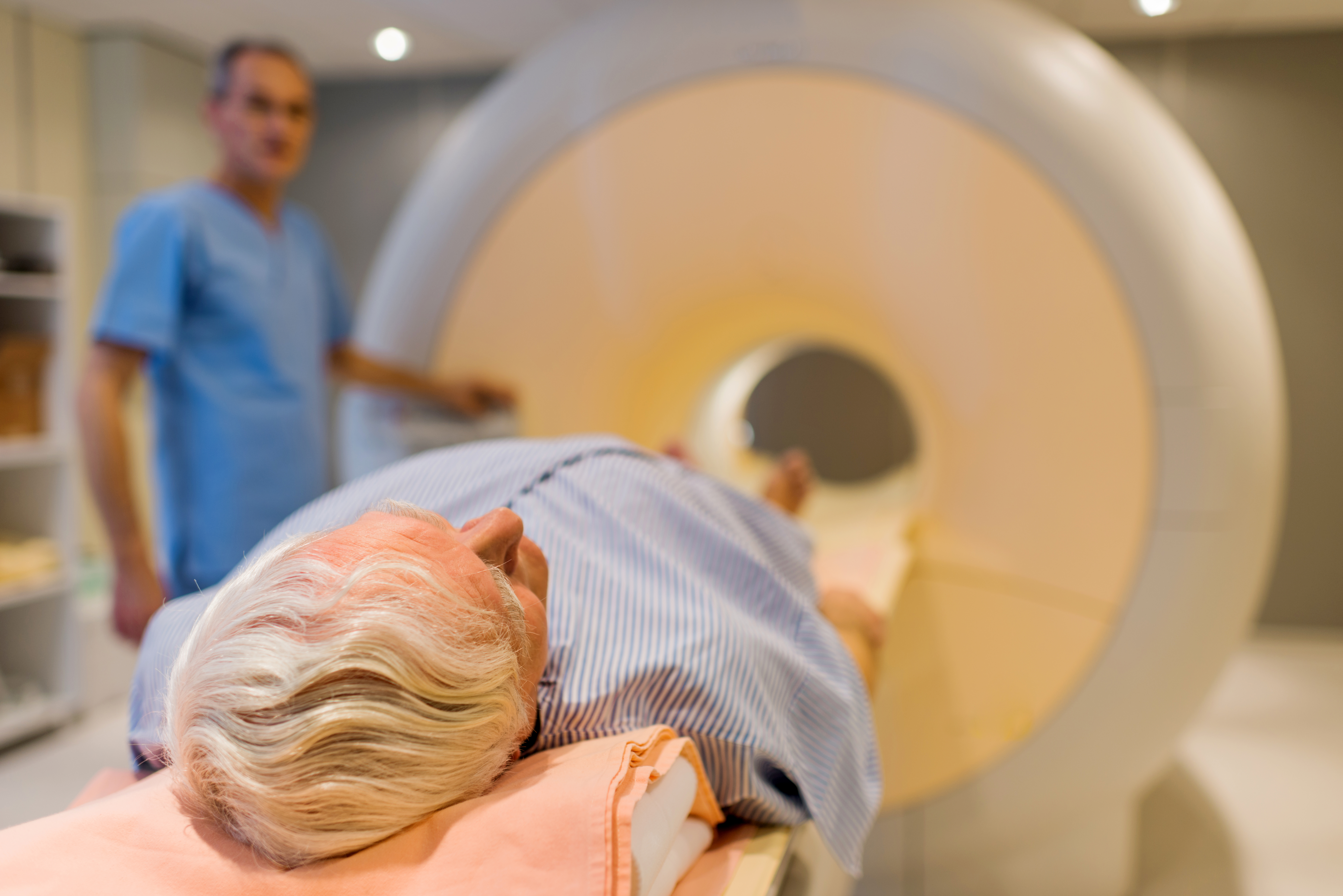 A senior man being guided into an MRI machine