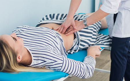 specialist performing physical assessment by applying pressure onto patients stomach