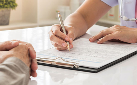close up of clinician writing notes during health assessment consultation