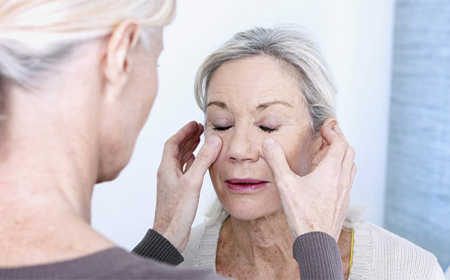 Plastic surgery consultation with a plastic surgeon performing physical assessment on elder woman's face