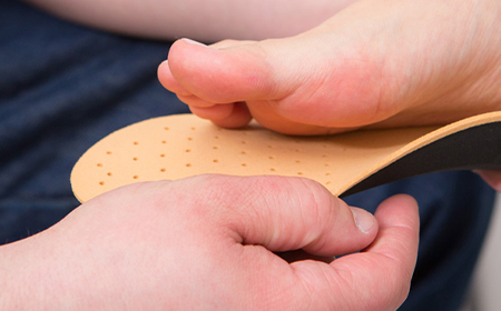 close up of specialist performing tests using shoe soles on patients foot