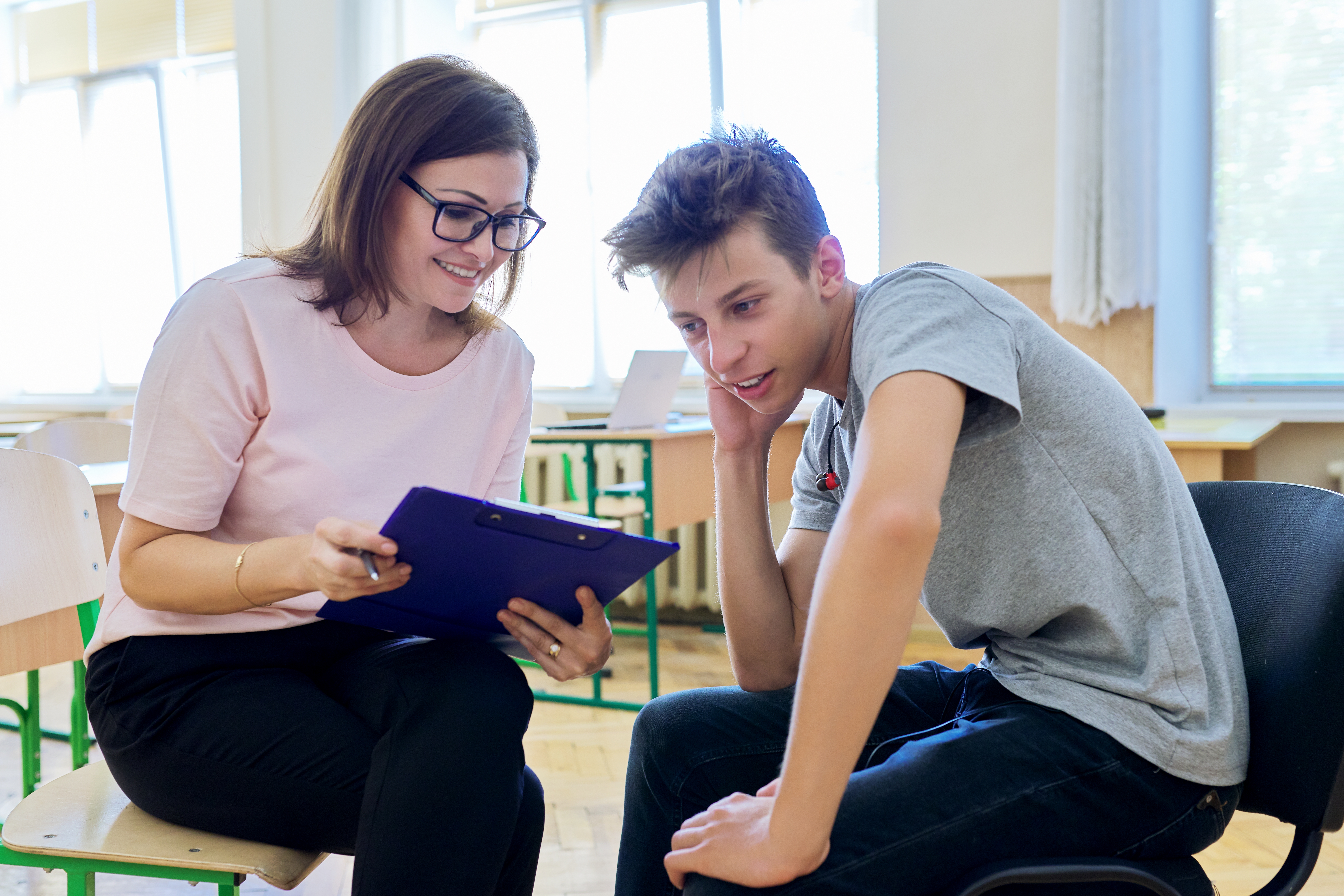 A female psychologist talking and helping a male teenager