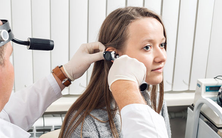close up of ear specialist looking at patients ear