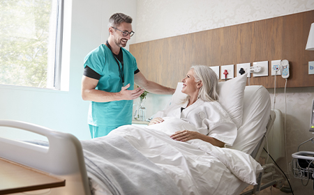 Female patient in hospital bed speaking to male nurse about women's health issues