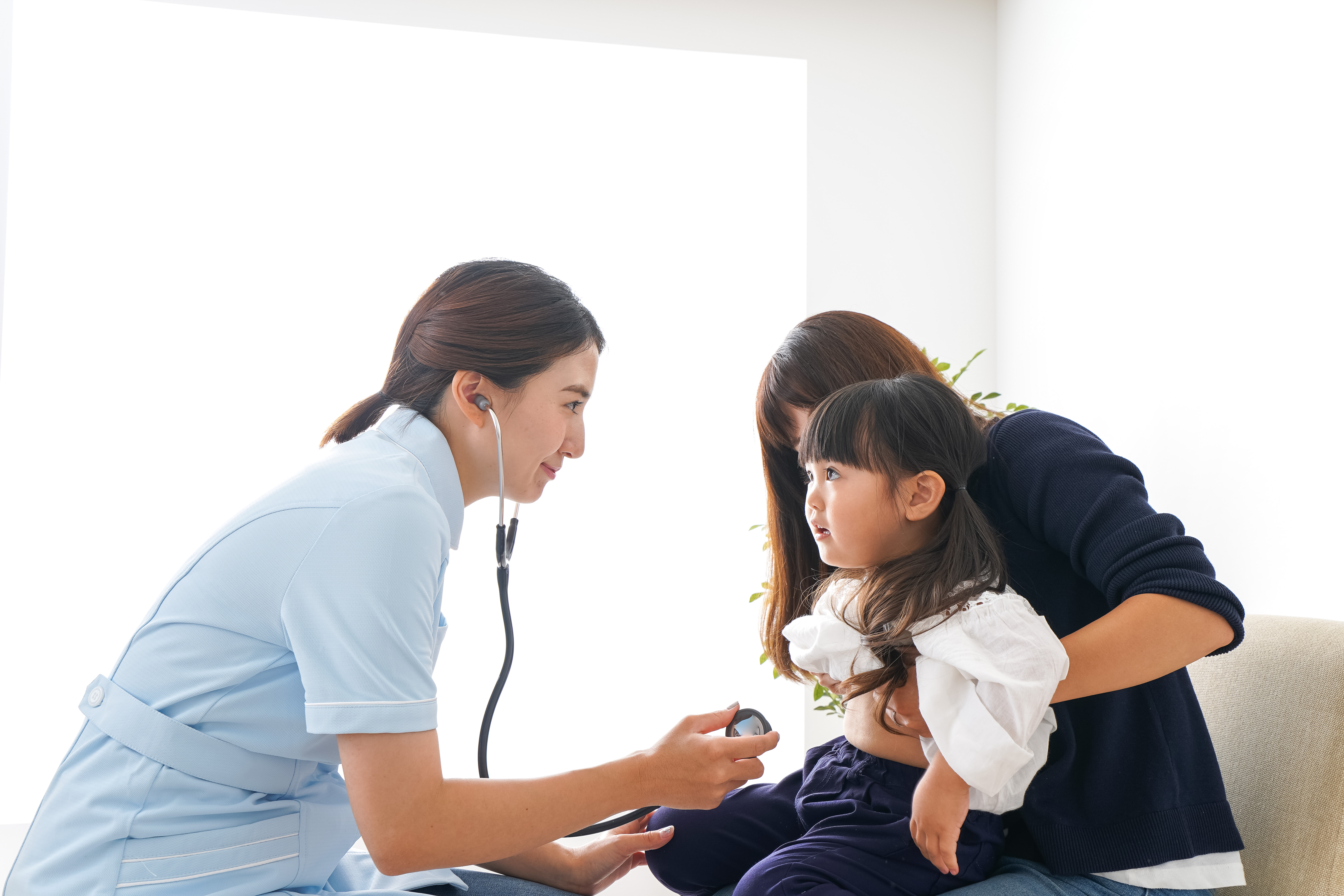 A female doctor listens to a young girl's chest with a stethoscope