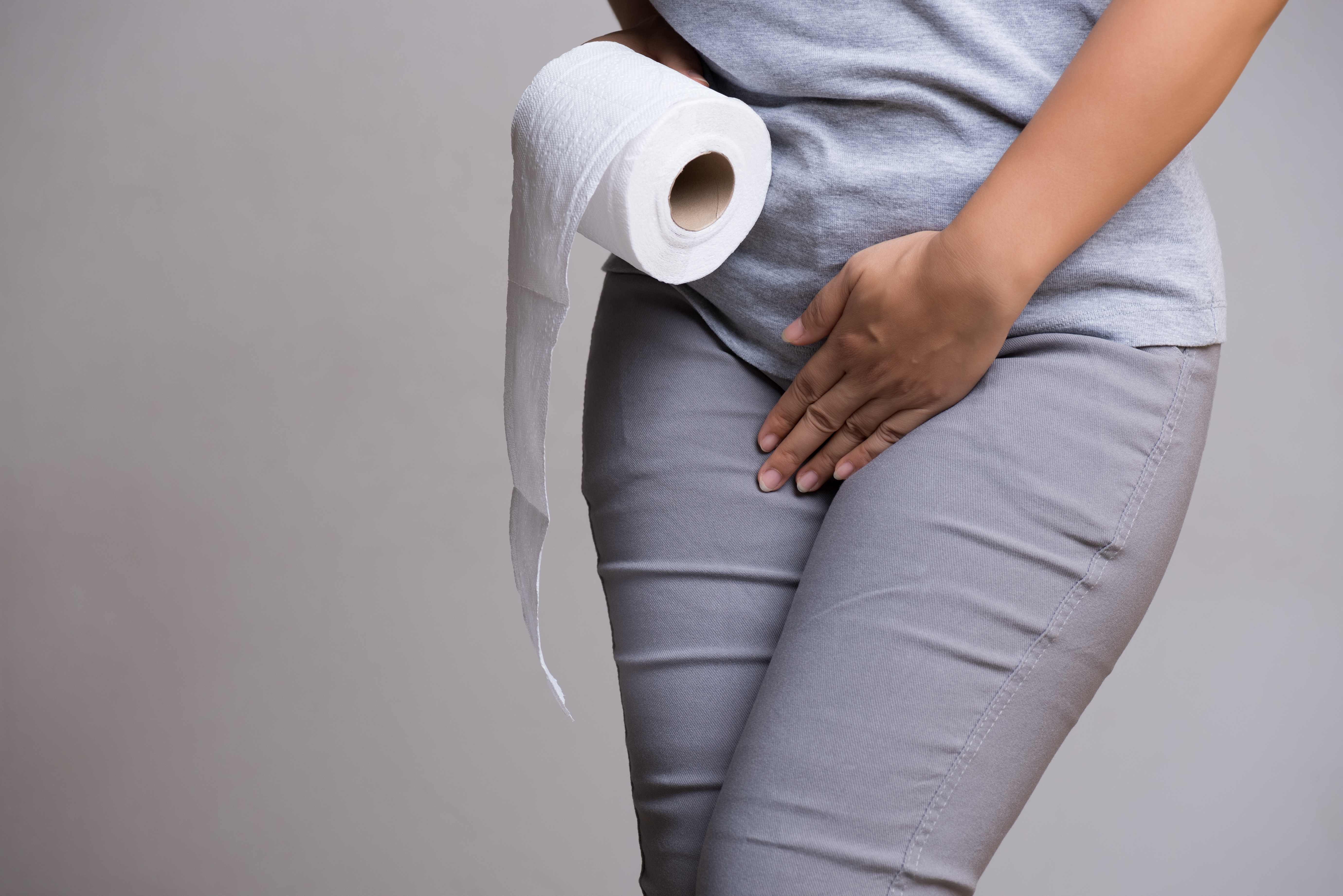 A woman holding her crotch and toilet roll