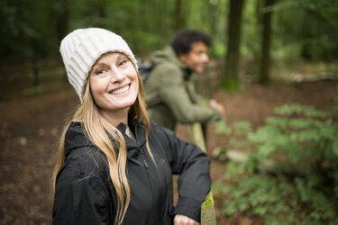 A woman standing outside in a white hat smiling at the camera